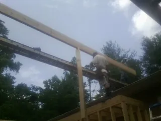 Carpenter setting a ridge beam over a new addition frame — Ice Dam Removal by Roofing Brothers in Demorest