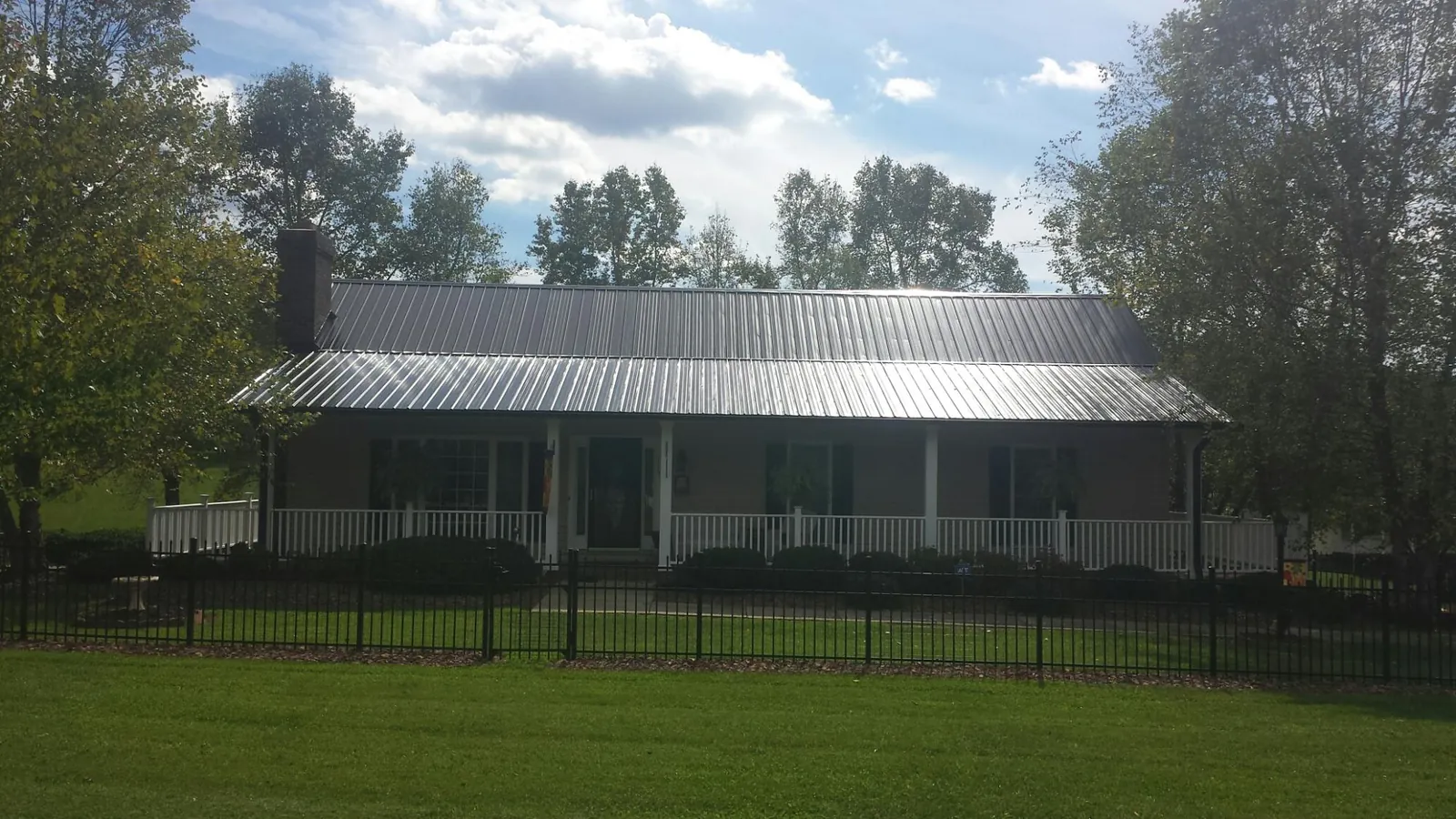 Gray metal roof on a brick ranch with a full width front porch — Gutter Guard Installation work by our crew in Demorest