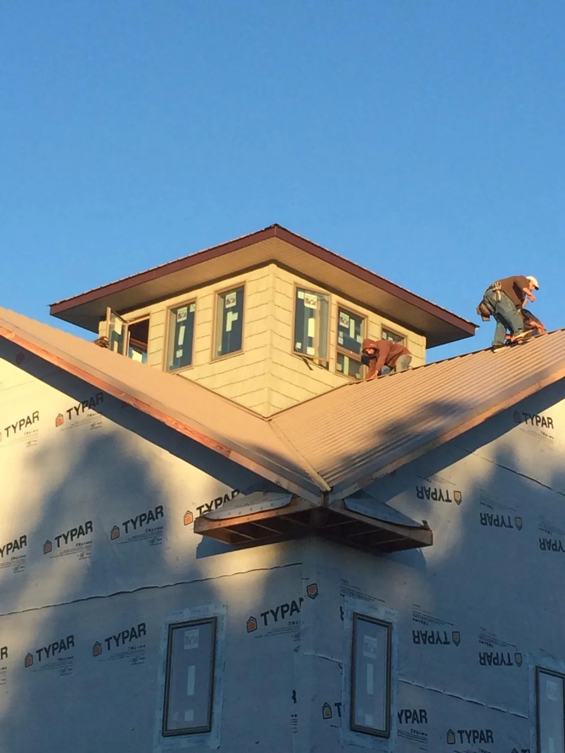 Roofers working around a rooftop cupola on a new metal roof at sunset — Roof Waterproofing in Demorest by Roofing Brothers